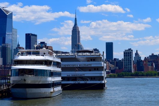 Cruise vessels docked in New York with Manhattan skyline in the background.