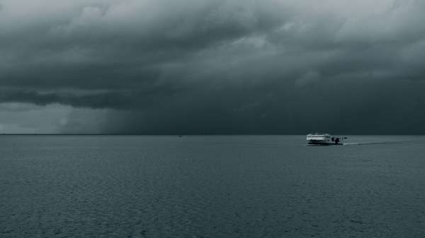 Vessel at sea under dark clouds.