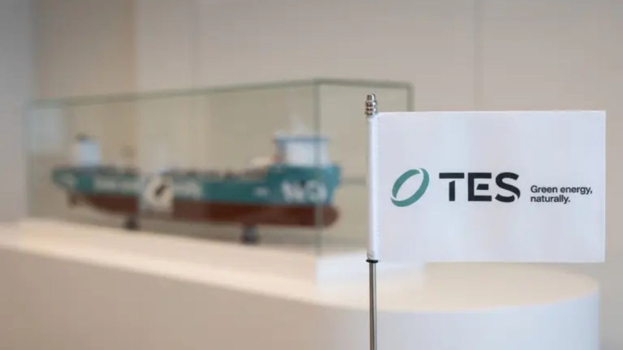 TES flag with a model vessel in the background.