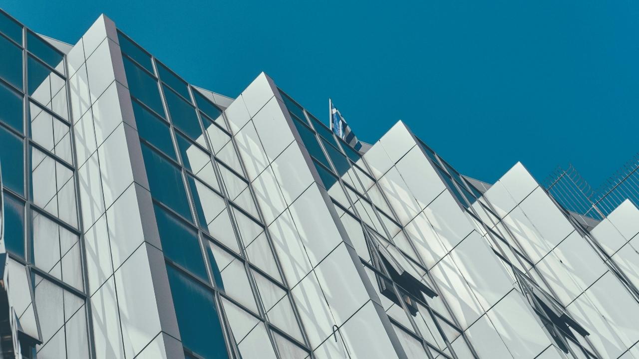 Modern building facade with flag of Greece on top.